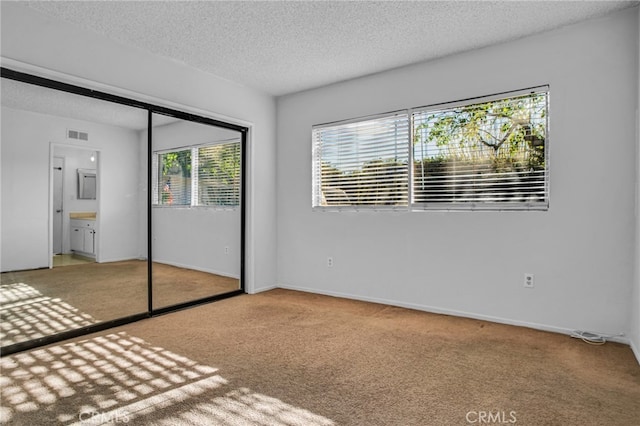 unfurnished bedroom featuring a textured ceiling, visible vents, a closet, and carpet floors