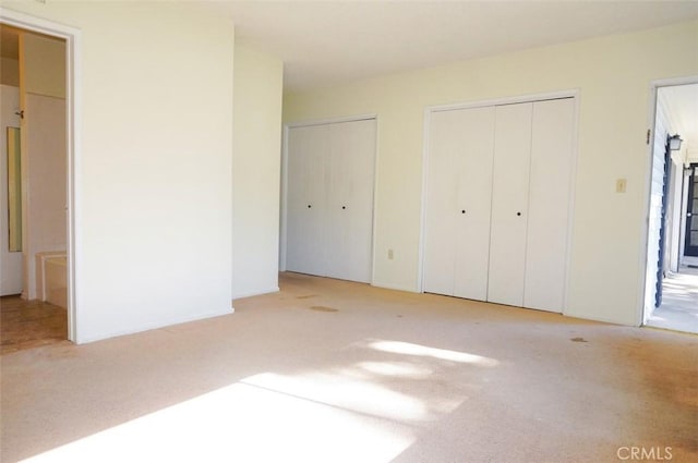 unfurnished bedroom with carpet floors and multiple closets