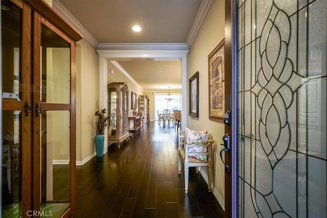 hall with baseboards, dark wood-style flooring, crown molding, and a notable chandelier