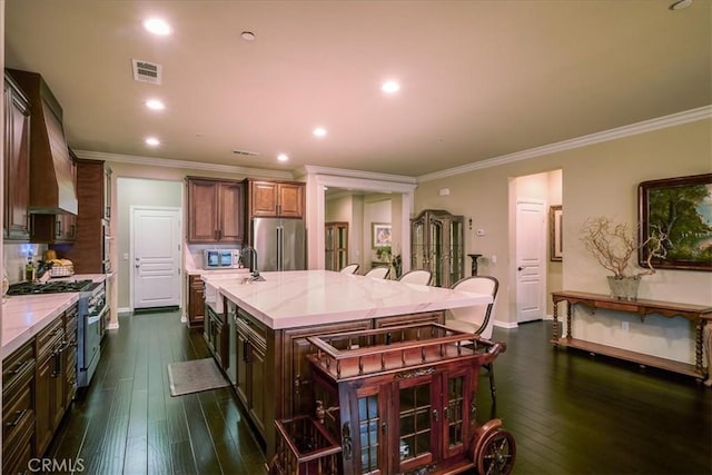 kitchen featuring a large island, high end appliances, ornamental molding, and visible vents