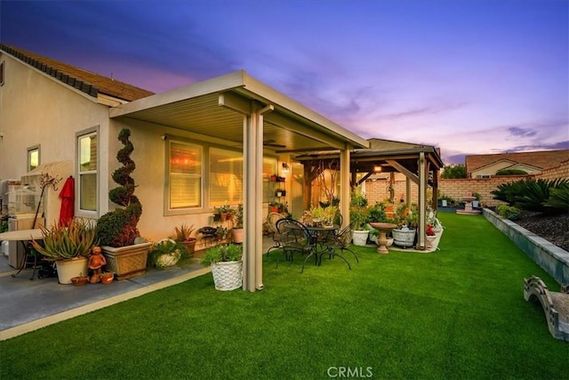 back of house featuring ceiling fan, fence, stucco siding, a patio area, and a yard