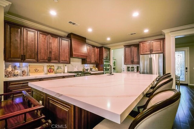 30459 Cowboy Ln, Menifee, CA 92584 - kitchen featuring premium range hood, stainless steel appliances, dark wood-type flooring, a large island with sink, and light stone counters