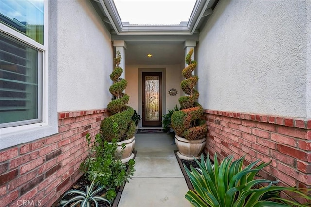 view of exterior entry with brick siding and stucco siding