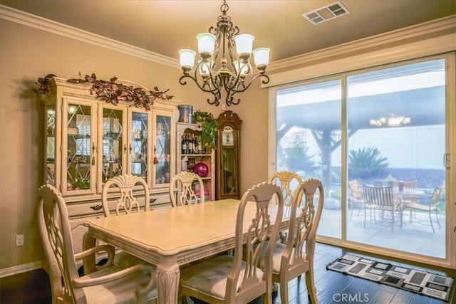 dining area featuring crown molding, a notable chandelier, visible vents, and wood finished floors