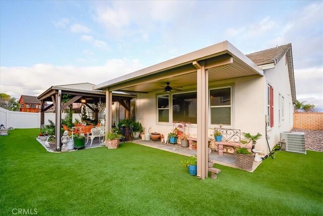 rear view of property with a ceiling fan, central AC unit, a patio area, a gazebo, and a fenced backyard