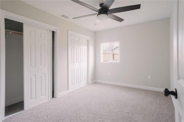 unfurnished bedroom with two closets, visible vents, baseboards, and carpet