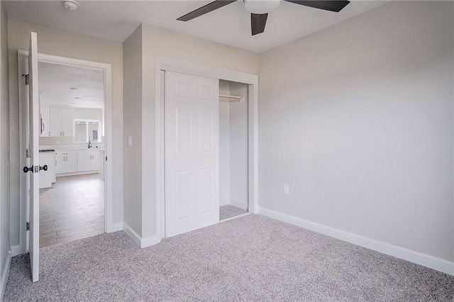 unfurnished bedroom featuring a sink, a closet, carpet flooring, baseboards, and ceiling fan