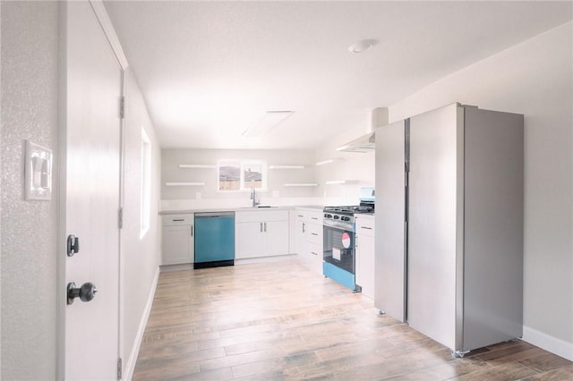 kitchen featuring light wood finished floors, open shelves, a sink, appliances with stainless steel finishes, and wall chimney range hood