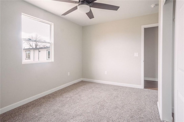 carpeted spare room featuring baseboards and ceiling fan