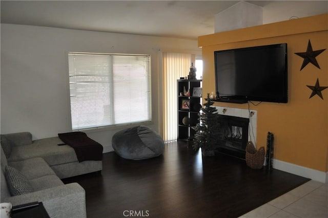 living room with a healthy amount of sunlight, a fireplace, baseboards, and wood finished floors