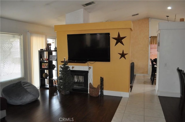 living area with light tile patterned floors, visible vents, baseboards, and a tiled fireplace