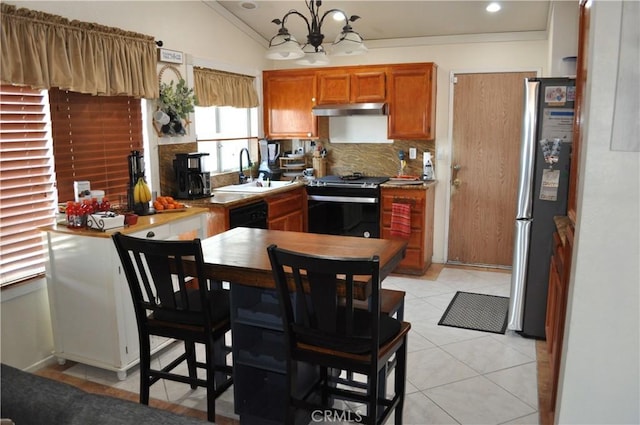 kitchen featuring brown cabinetry, freestanding refrigerator, a sink, stove, and under cabinet range hood