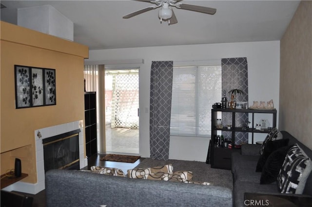 living room featuring a tiled fireplace and ceiling fan