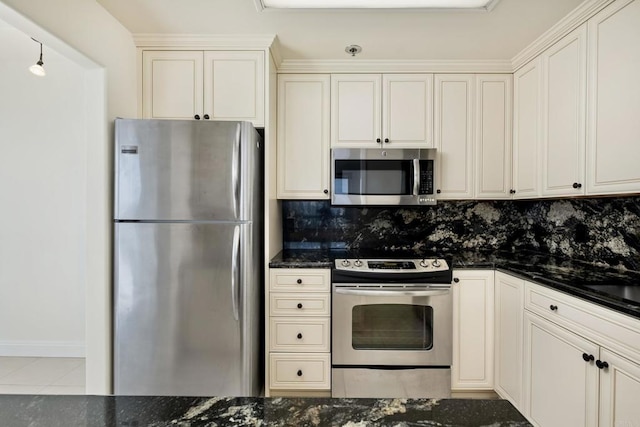 kitchen with tile patterned flooring, backsplash, appliances with stainless steel finishes, and dark stone counters