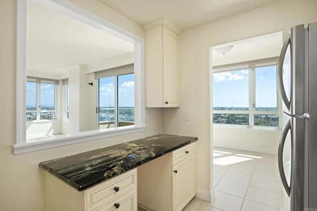 kitchen with light tile patterned floors, baseboards, white cabinetry, and freestanding refrigerator