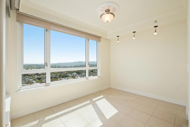 empty room featuring light tile patterned floors, baseboards, and crown molding