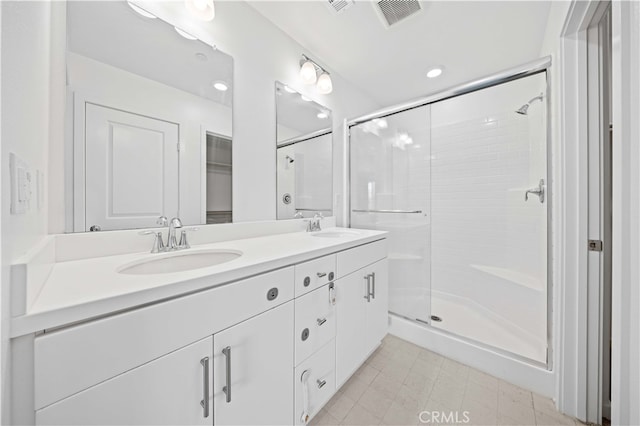 full bathroom featuring a shower stall, double vanity, visible vents, and a sink