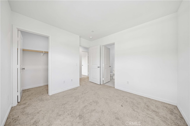 unfurnished bedroom featuring a spacious closet, a closet, baseboards, and carpet