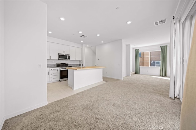kitchen with visible vents, light colored carpet, and appliances with stainless steel finishes