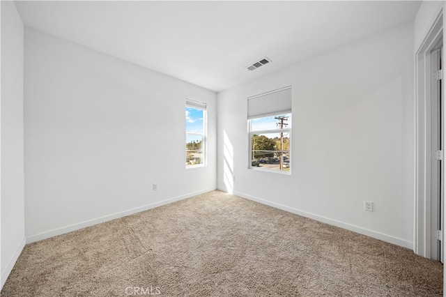 carpeted spare room featuring visible vents and baseboards