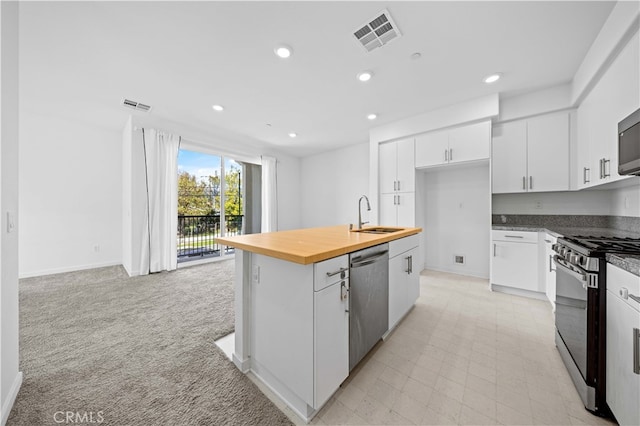 kitchen with visible vents, light carpet, a sink, wood counters, and stainless steel appliances
