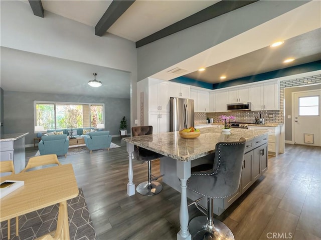 kitchen featuring backsplash, light stone countertops, stainless steel appliances, and dark wood-style floors