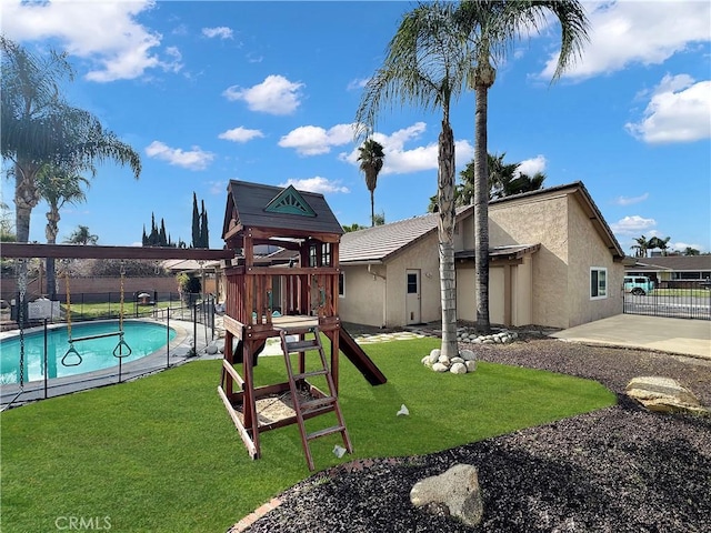 view of jungle gym featuring a lawn, fence, a fenced in pool, and a patio
