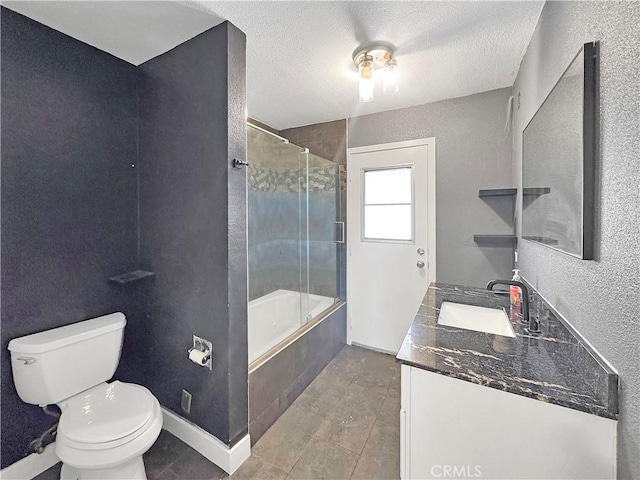 bathroom with a textured ceiling, toilet, bath / shower combo with glass door, and vanity