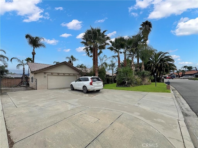 view of side of property featuring fence, a garage, concrete driveway, stucco siding, and a yard
