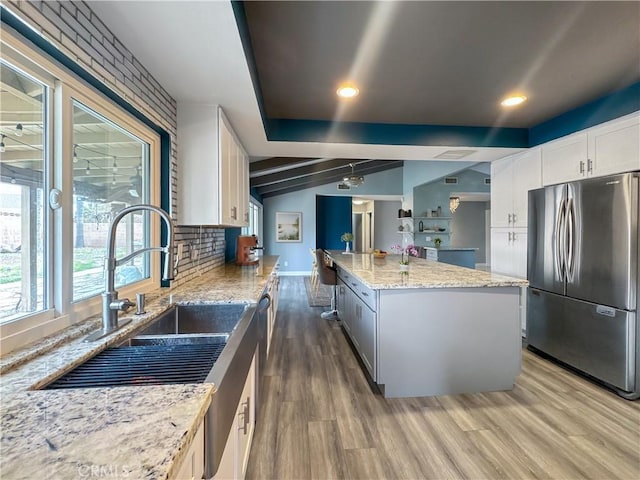 kitchen featuring freestanding refrigerator, a kitchen island, backsplash, and wood finished floors