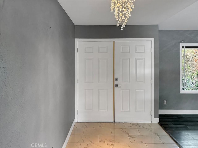 foyer with baseboards, marble finish floor, and a chandelier