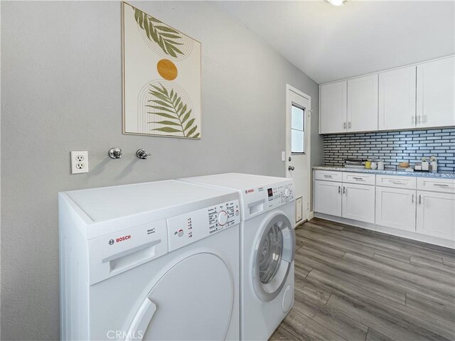 laundry area featuring separate washer and dryer, wood finished floors, and cabinet space