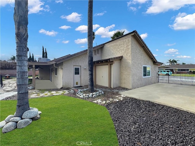 back of house with a patio, stucco siding, fence, and a yard