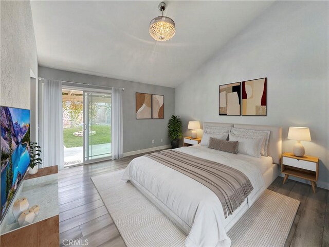 bedroom with baseboards, access to outside, vaulted ceiling, and wood finished floors