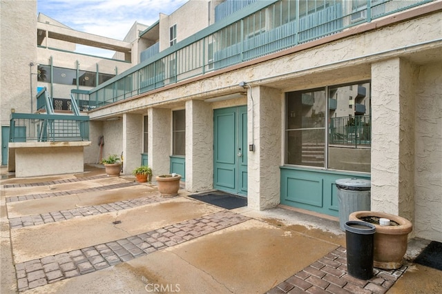 doorway to property featuring a patio, stucco siding, and a balcony