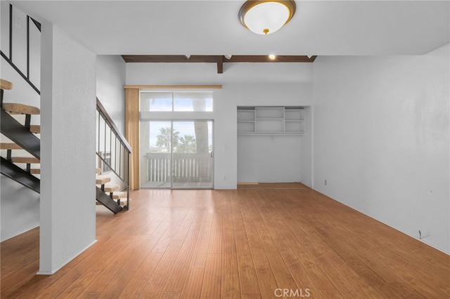 interior space with stairway, beamed ceiling, and wood-type flooring