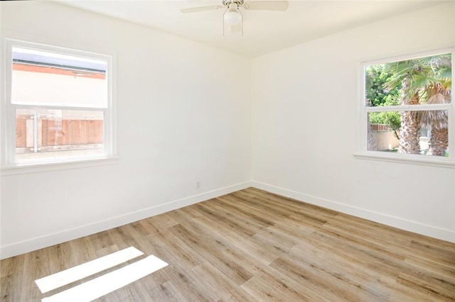 empty room featuring a ceiling fan, light wood-type flooring, and baseboards