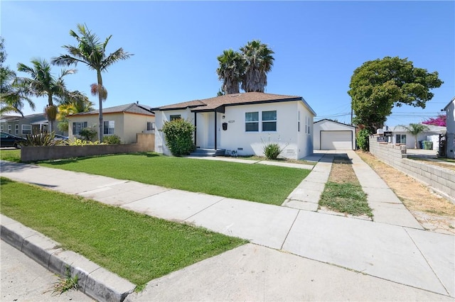 view of front of house with fence, concrete driveway, a front yard, stucco siding, and an outbuilding