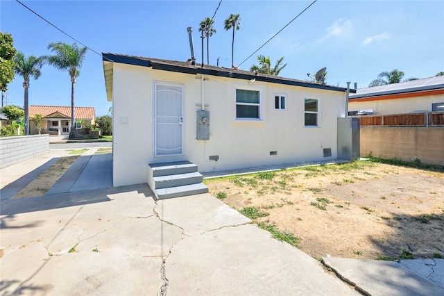 back of property with crawl space, stucco siding, and fence