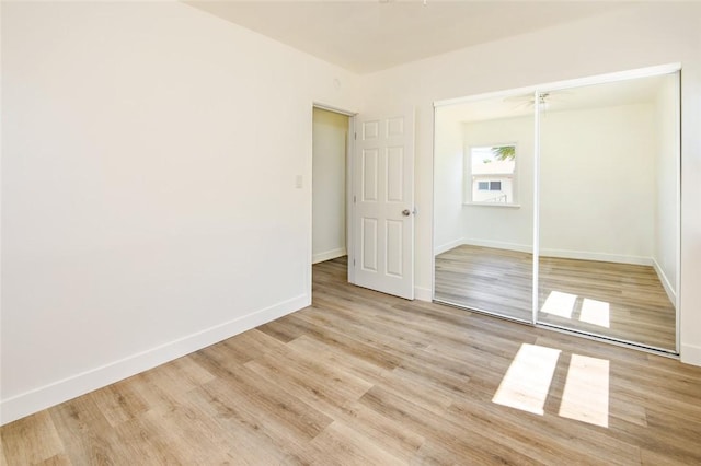 unfurnished bedroom with a closet, baseboards, and light wood finished floors