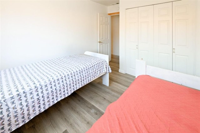 bedroom with wood finished floors and a closet