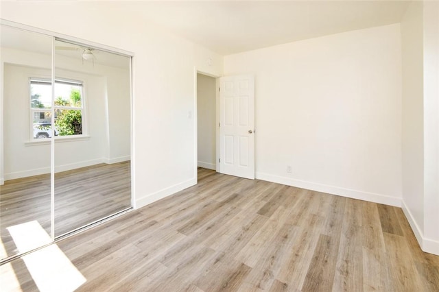 unfurnished bedroom featuring a closet, light wood-type flooring, and baseboards