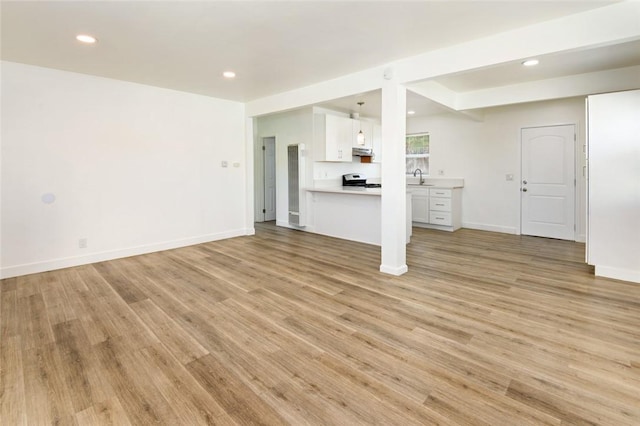 unfurnished living room featuring recessed lighting, baseboards, and light wood-style floors