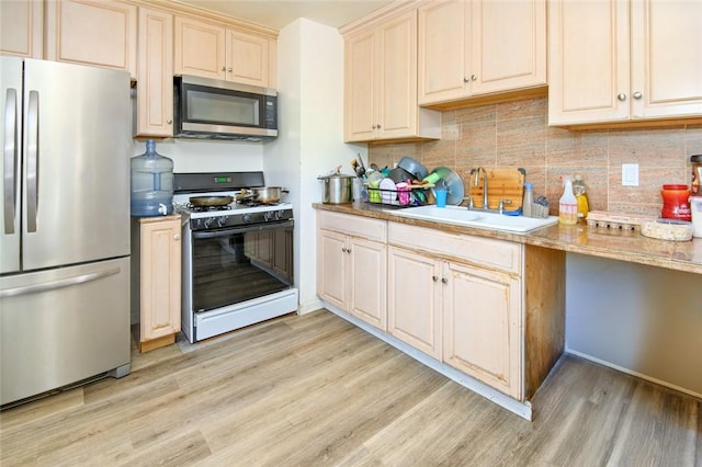 kitchen with light wood finished floors, backsplash, stainless steel appliances, and a sink