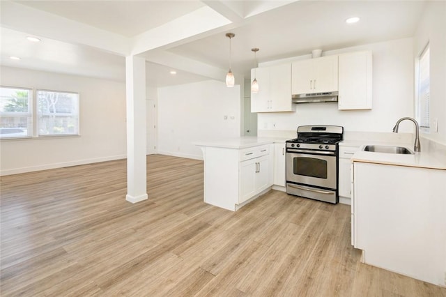 kitchen featuring under cabinet range hood, a sink, open floor plan, gas stove, and a peninsula