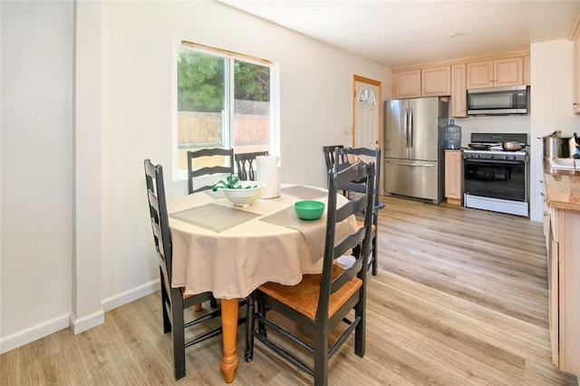 dining area with light wood-type flooring and baseboards