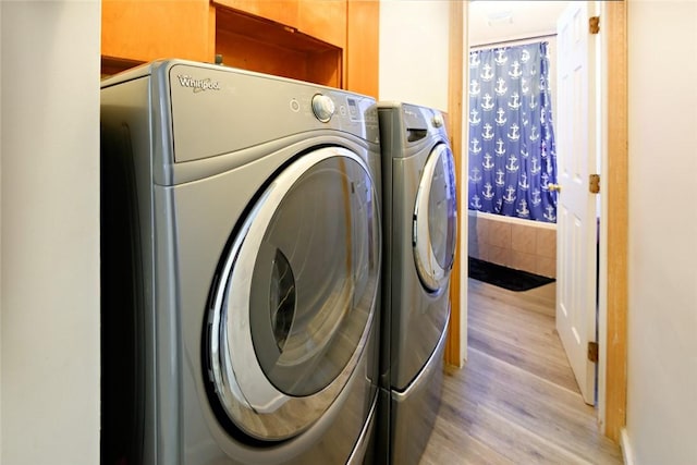 clothes washing area with light wood-type flooring, independent washer and dryer, and laundry area