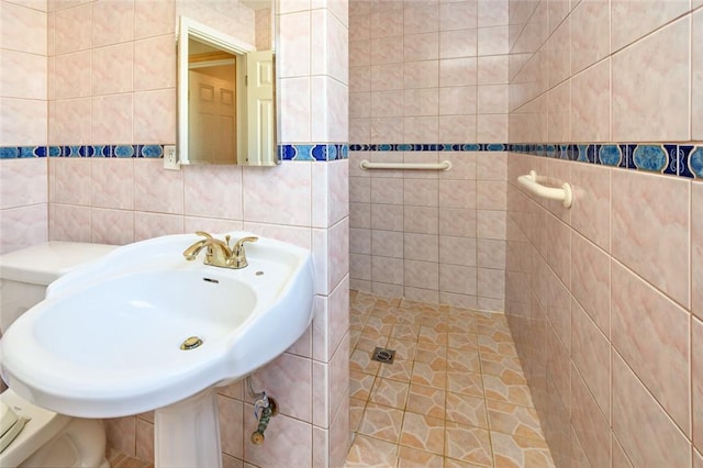 full bathroom with a sink, toilet, tile walls, and a tile shower