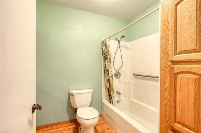 bathroom featuring shower / bathtub combination with curtain, baseboards, toilet, and wood finished floors