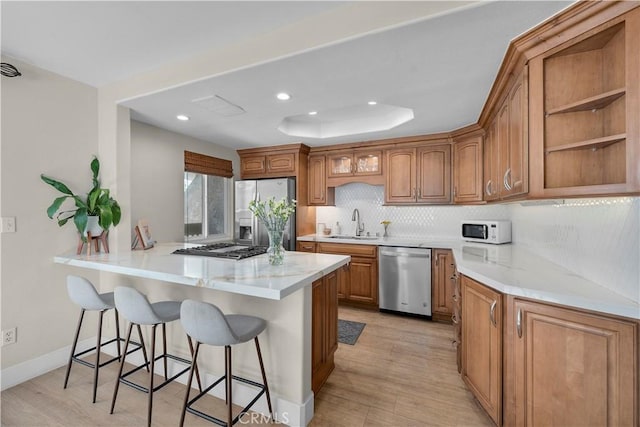 2204 Vanderbilt Ln Unit 16, Redondo Beach, CA 90278 - kitchen with a peninsula, a kitchen breakfast bar, decorative backsplash, and appliances with stainless steel finishes